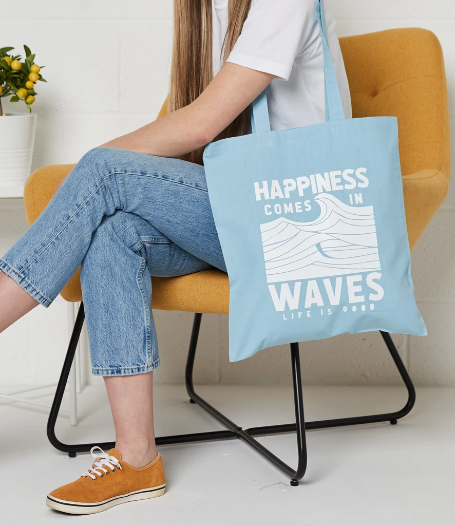 Woman sitting with blue printed long handled cotton shopper over shoulder