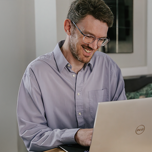 Man smiling looking into laptop in PenCarrie HQ