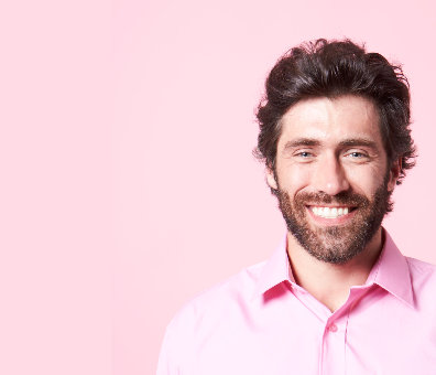 A smiling man in a pink shirt against a pink backdrop